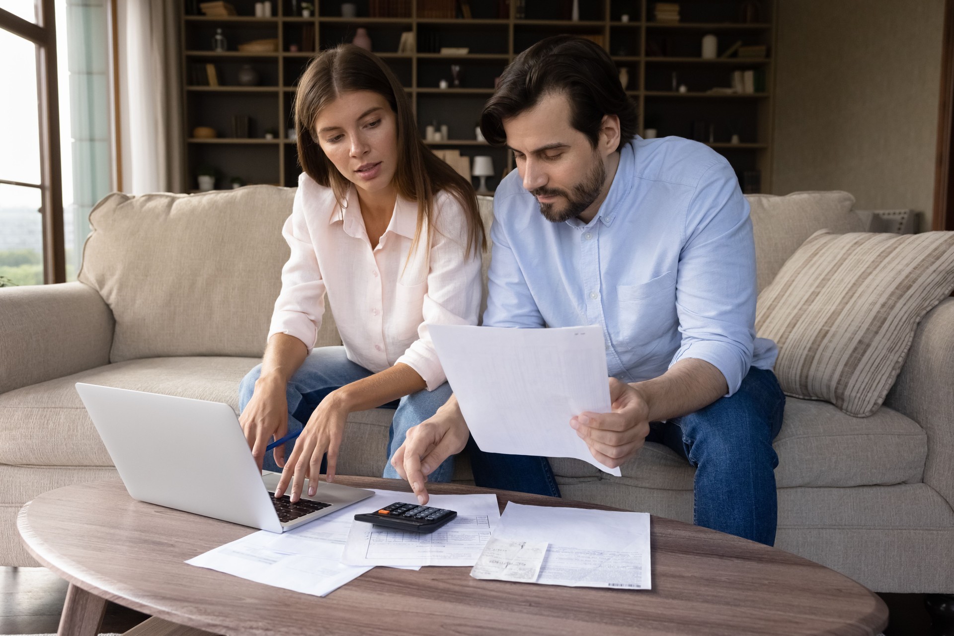 Concentré jeune couple familial calculant les dépenses.